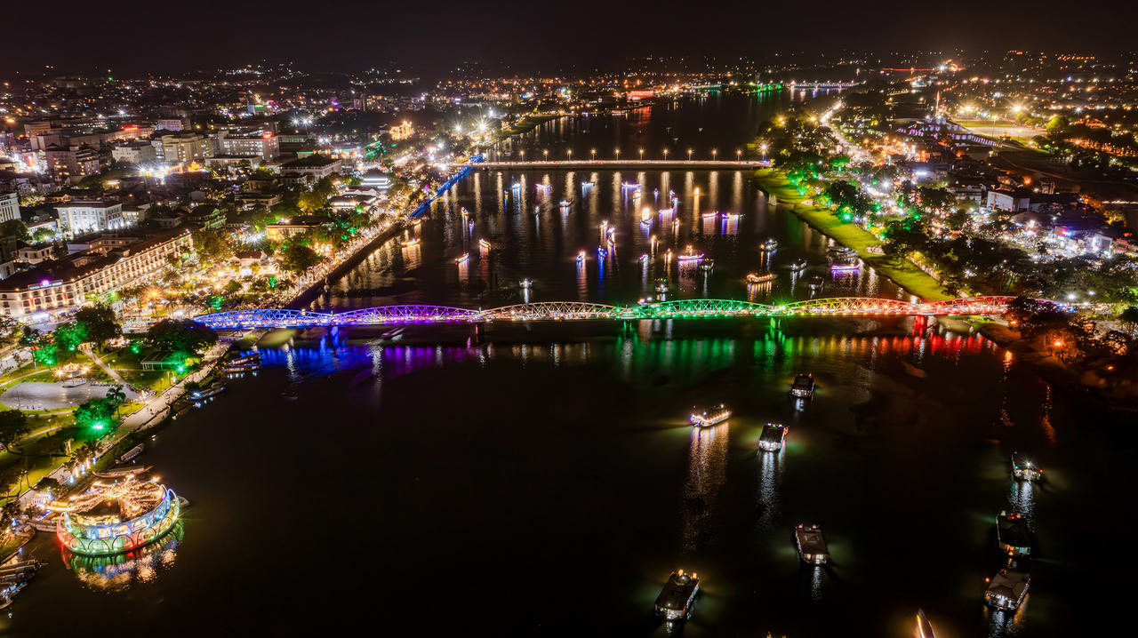 Ánh đèn lung linh phản chiếu xuống mặt nước khiến cầu Trường Tiền trở nên rực rỡ, mang một vẻ đẹp vừa cổ kính vừa hiện đại.