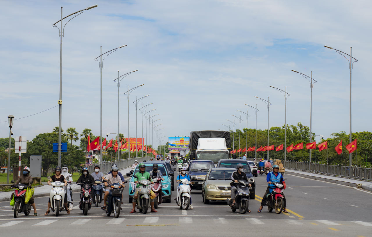 Giữa sắc cờ đỏ bay trong gió, dòng xe qua cầu Phú Xuân nhộn nhịp nối dài như nhịp thở không ngừng của thành phố bên dòng Hương Giang