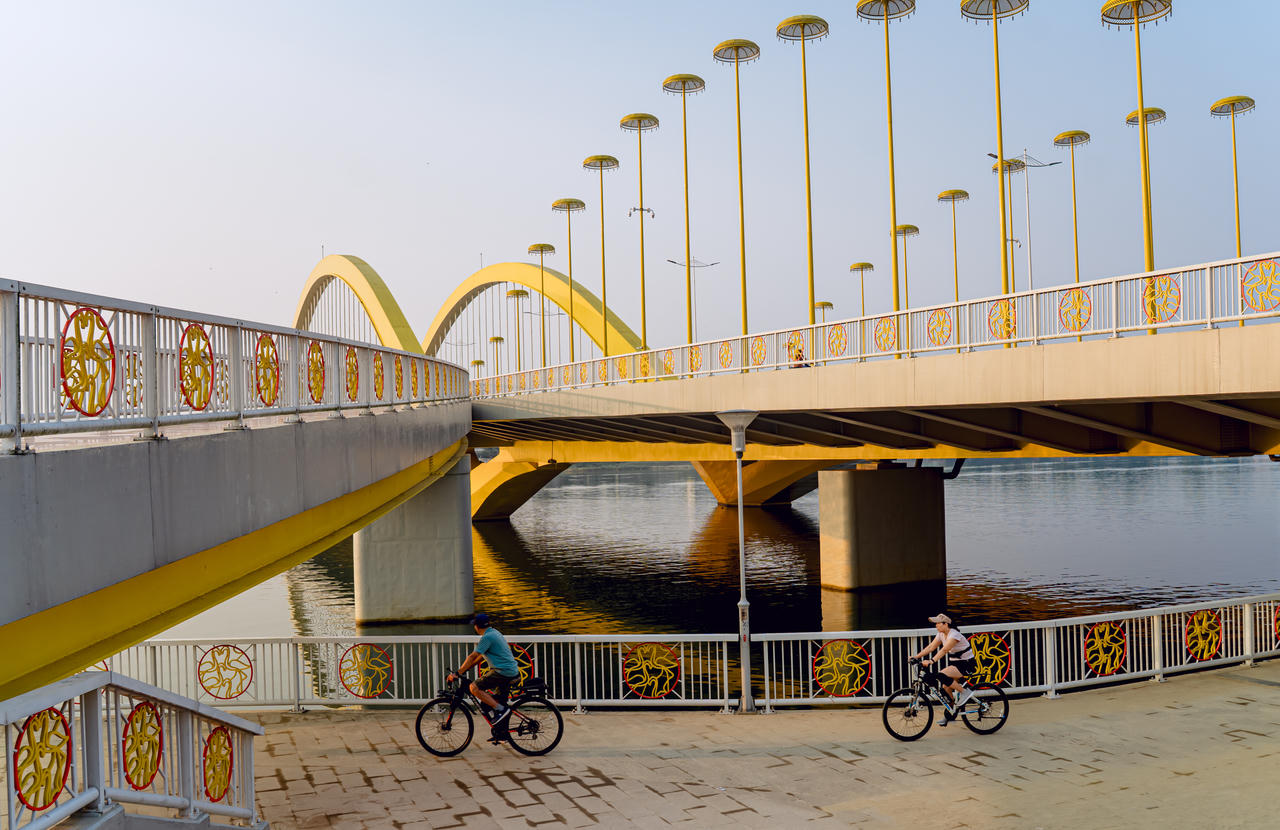 Dưới chân cầu, người dân thong dong đạp xe bên dòng Hương gợi nét yên bình, thơ mộng của Huế - thành phố hạnh phúc.