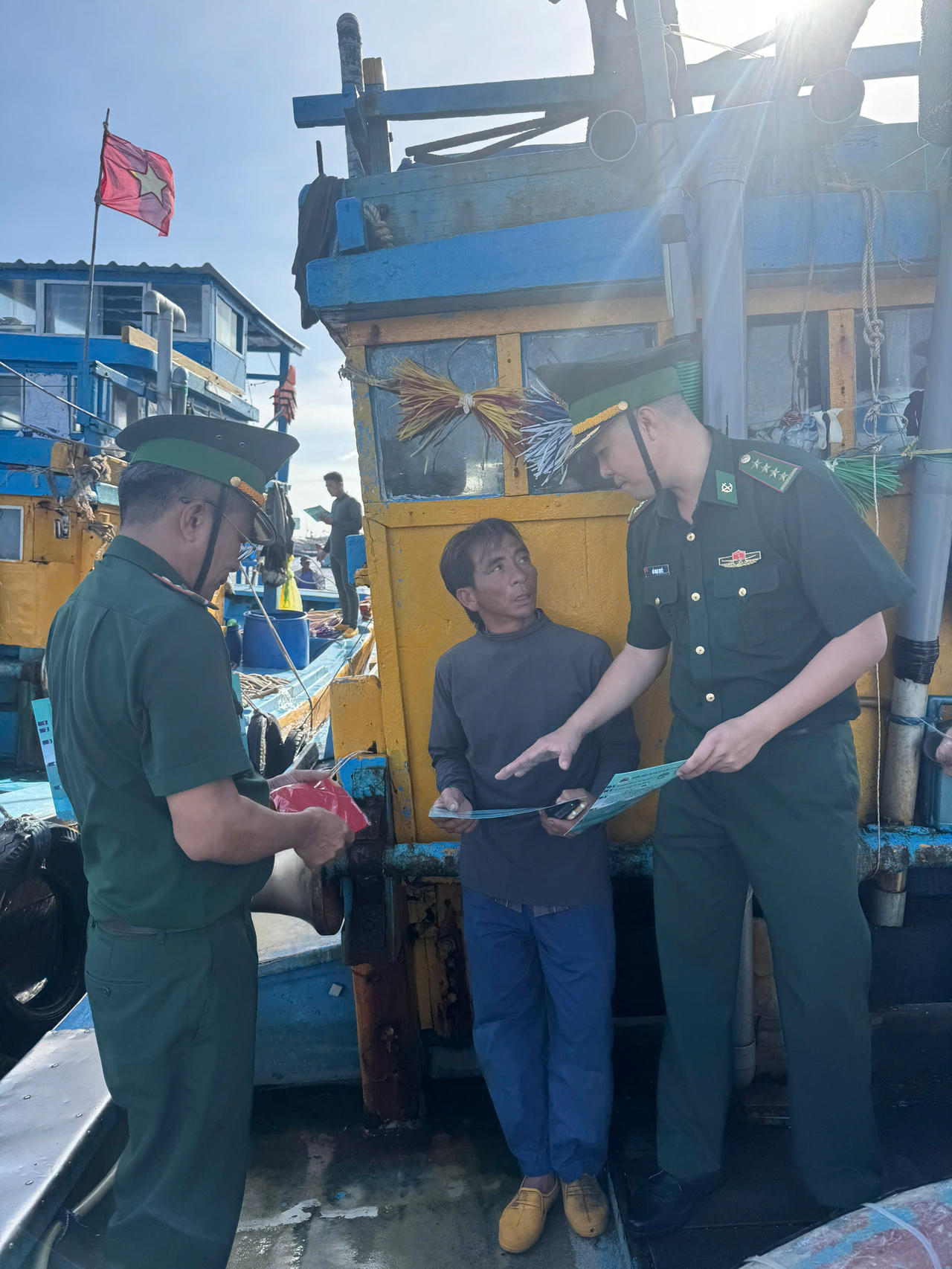 Đại úy Đỗ Ngọc Quyết, Chính trị viên phó và Trạm trưởng Nguyễn Duy Tân tuyên truyền pháp luật cho ngư dân tại bến cảng.