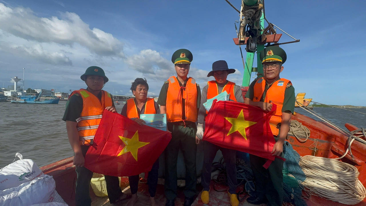 Cán bộ, chiến sĩ Đồn Biên phòng Bình Châu trực tiếp lên tàu tuyên truyền quy định chống khai thác IUU, kết hợp tặng cờ Tổ quốc cho ngư dân vươn khơi.