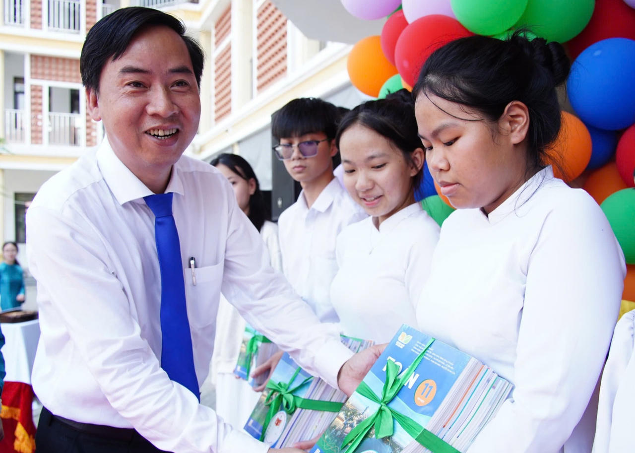 Ông Lê Phú Nguyện, Chủ tịch UBND xã Hoà Vang trao sách giáo khoa cho các em học sinh.