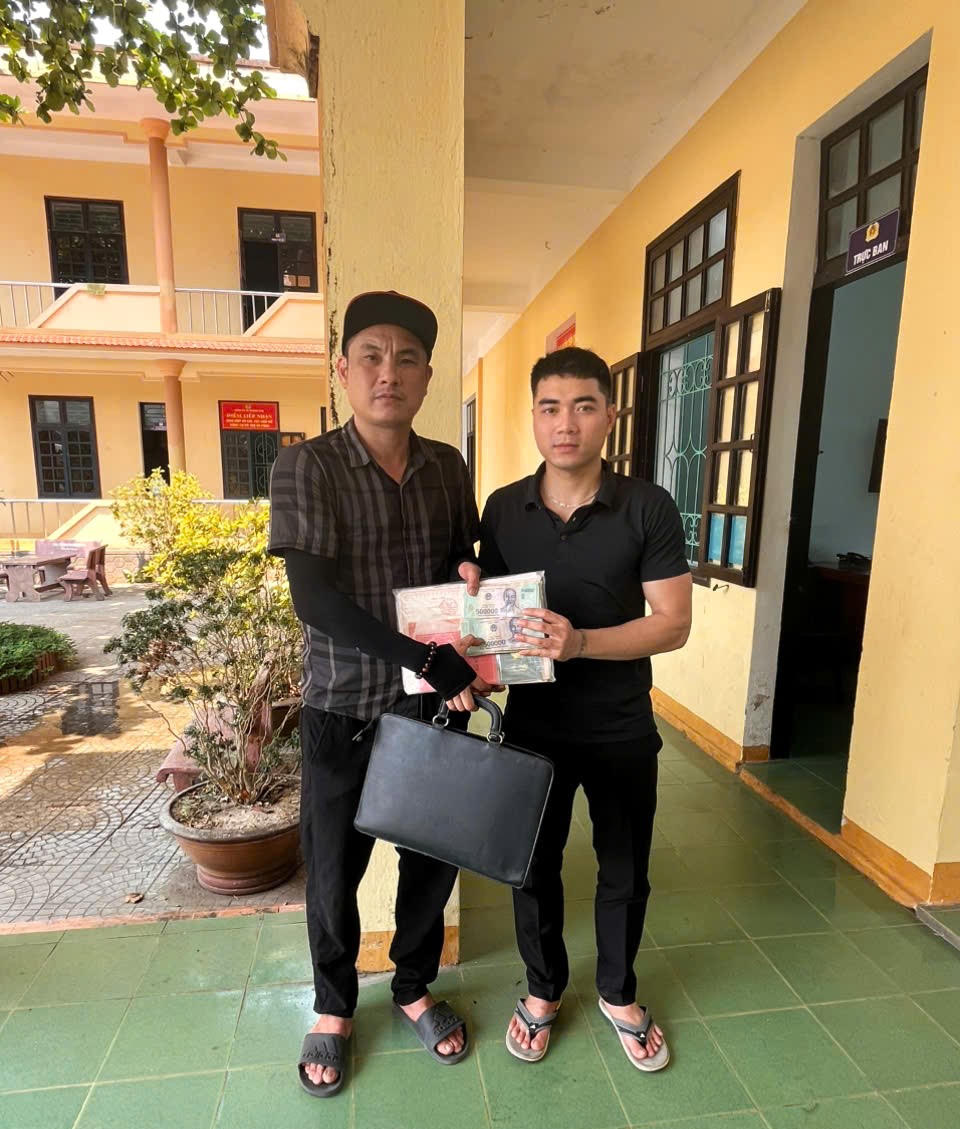 Anh Hoàng Huy Nguyên (phải) trao lại số tiền và giấy tờ nhặt được cho anh Nguyễn Quốc Hưng tại trụ sở Công an xã Trường Phú.