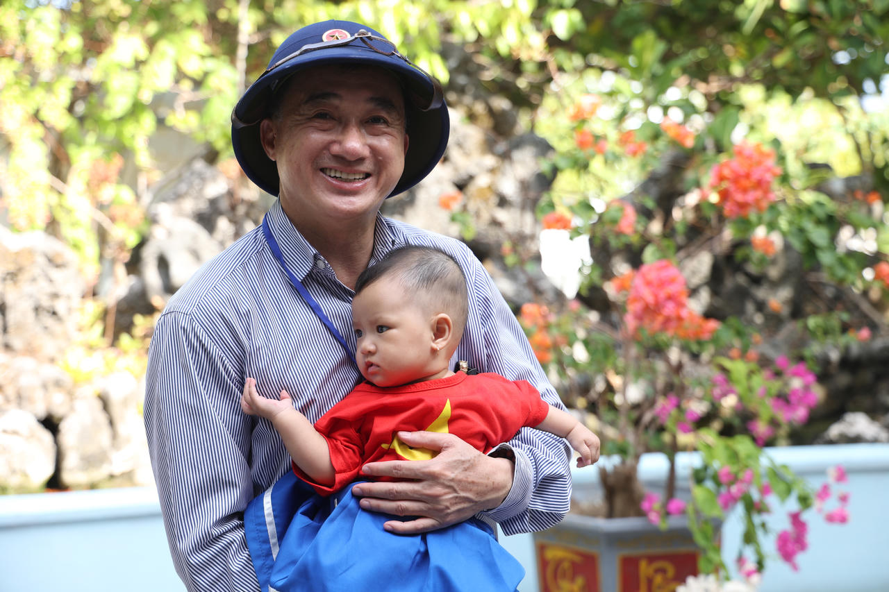 Thứ trưởng Trần Văn Thuấn bế em bé tại đảo Sinh Tồn Đông.