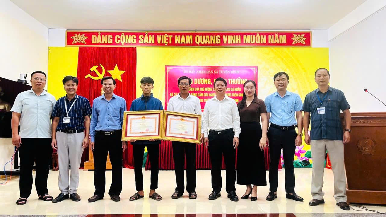 Lãnh đạo Ban Thi đua - Khen thưởng tỉnh cùng lãnh đạo xã Tuyên Bình chụp ảnh lưu niệm với hai cha con ông Cao Hữu Tình sau lễ trao Bằng khen của Thủ tướng Chính phủ vì hành động dũng cảm cứu người trên sông Gianh.