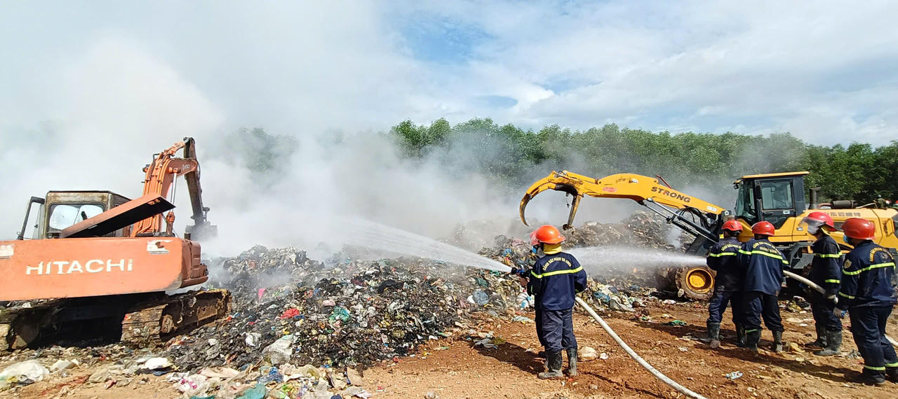 Lực lượng chức năng sử dụng máy múc và xe chữa cháy chuyên dụng để xử lý các điểm cháy âm ỉ tại khu xử lý rác Trường Thủy.