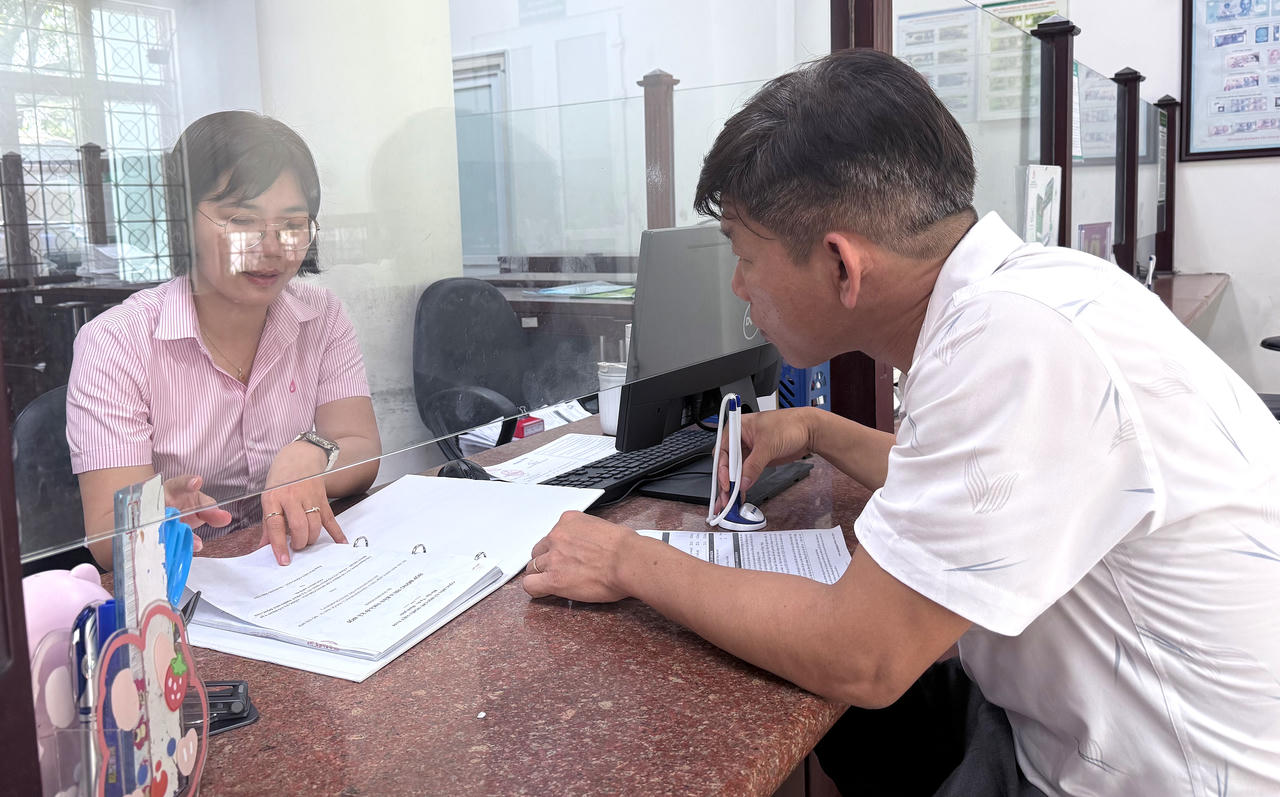 Cán bộ tín dụng NHCSXH TP Huế hướng dẫn người dân hoàn thiện các thủ tục giải ngân.