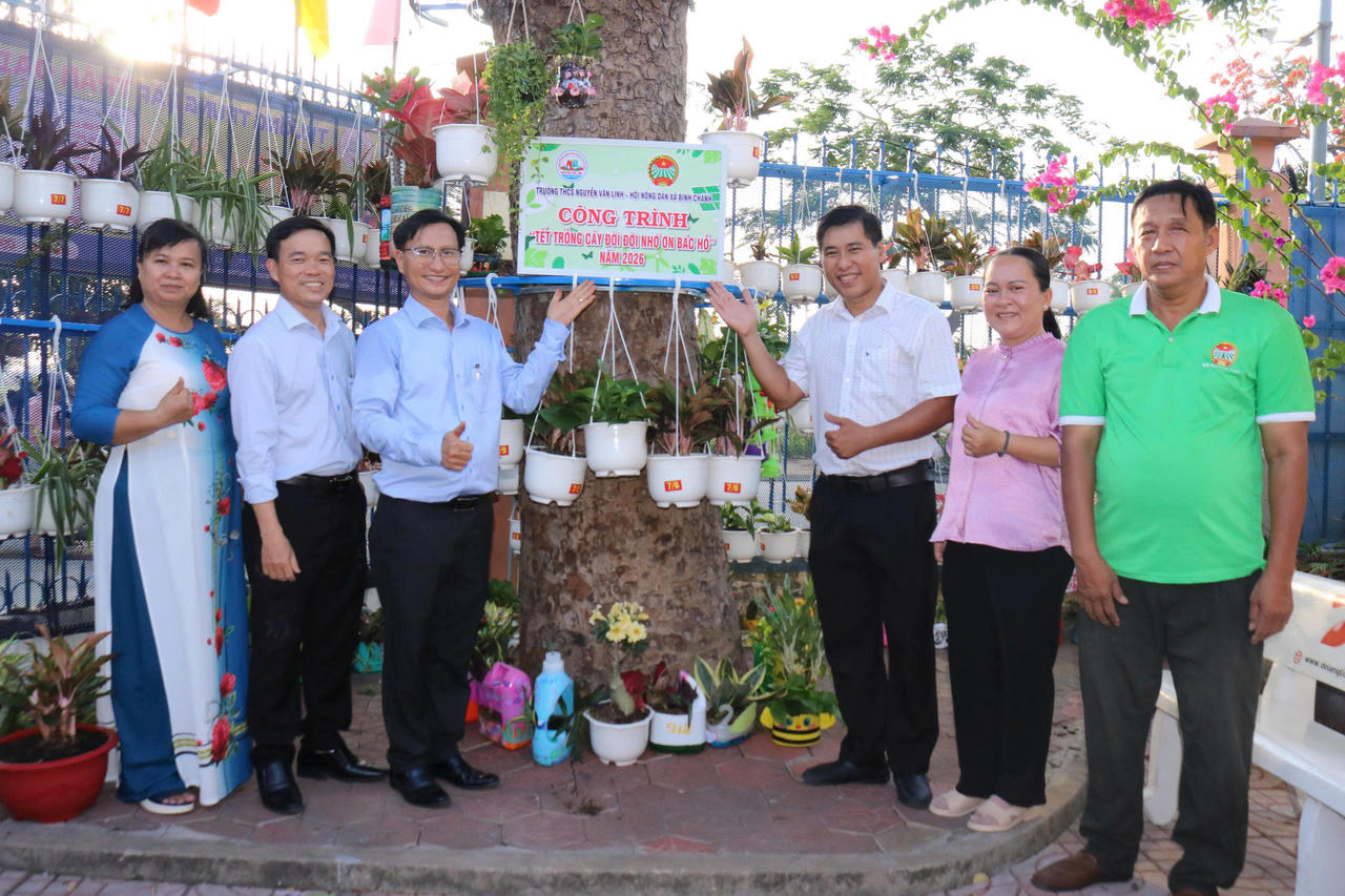 Đại diện Hội Nông dân xã Bình Chánh và Ban Giám hiệu Trường THCS Nguyễn Văn Linh bên công trình “Tết trồng cây đời đời nhớ ơn Bác Hồ” năm 2026.