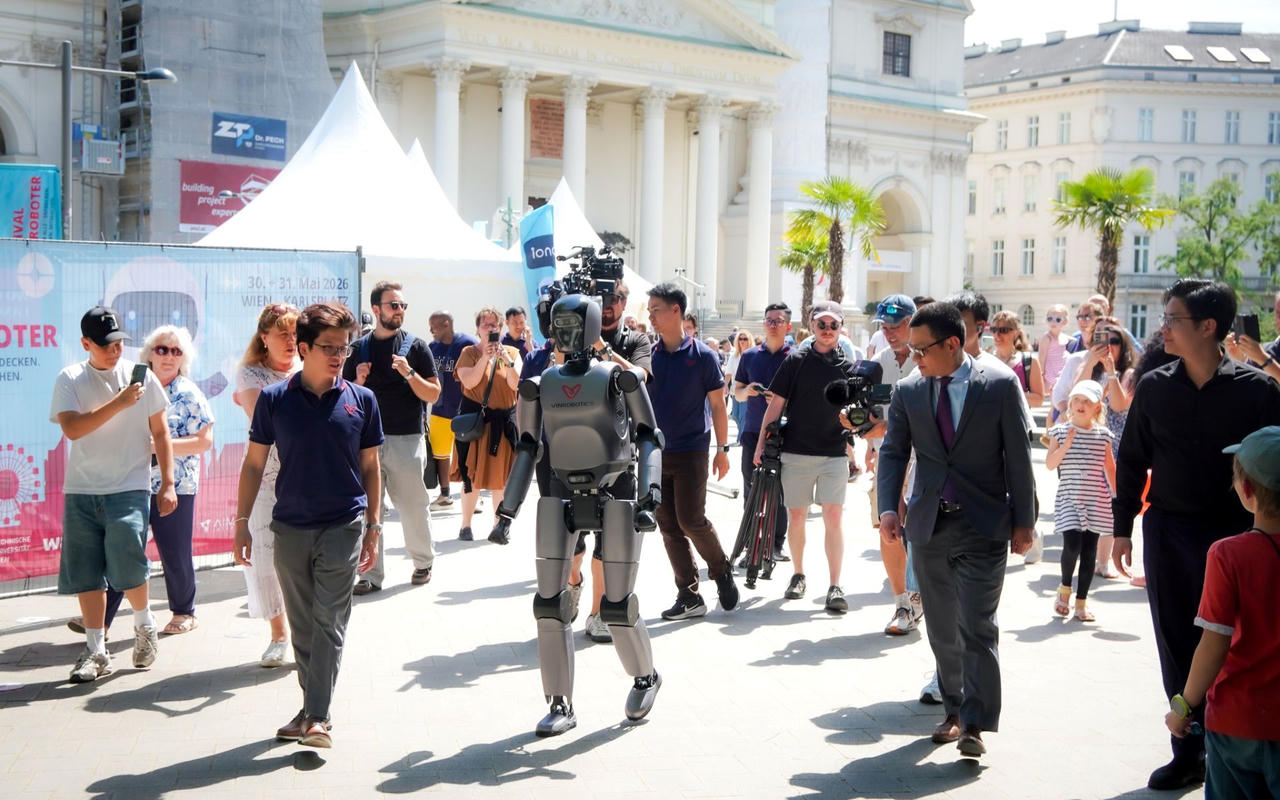 VR-H3 của VinRobotics thu hút sự chú ý với khả năng di chuyển tự nhiên tại Festival der Roboter 2026, dưới sự chứng kiến của Đại sứ Việt Nam tại Áo, ông Vũ Lê Thái Hoàng (thứ hai từ phải sang trái, hàng trên), cùng đông đảo khách tham quan quốc tế. (Nguồn: VinRobotics)