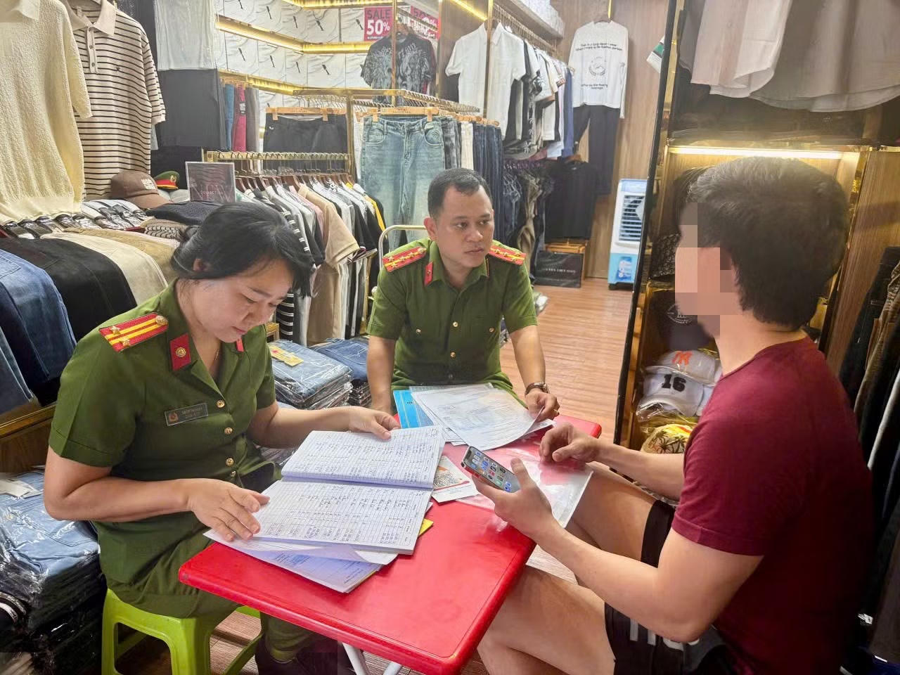 Cơ quan Công an kiểm tra làm việc với chủ một cửa hàng kinh doanh thời trang quần áo.