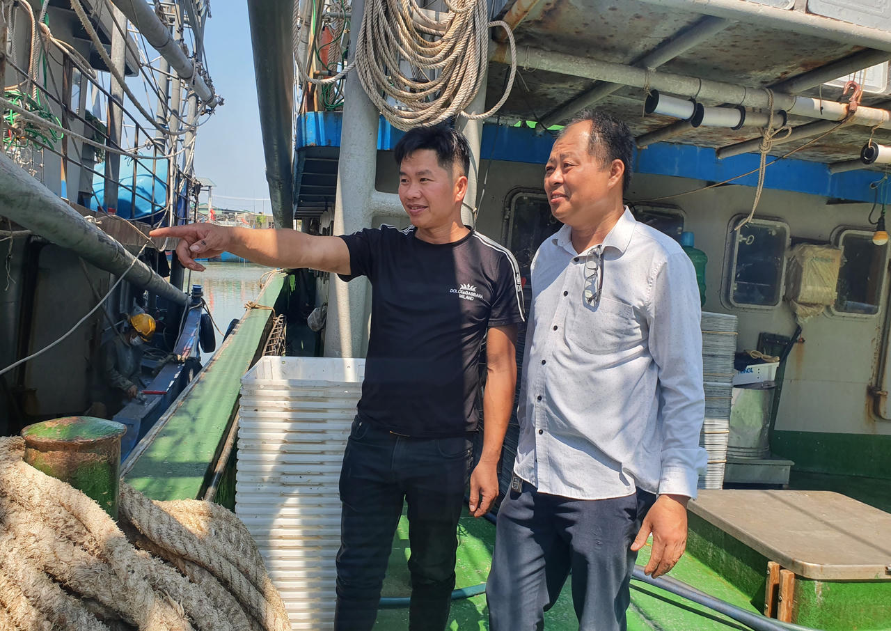 Đại diện Ban quản lý cảng cá Lạch Quèn (áo trắng) trao đổi với ngư dân về hoạt động của tàu cá.