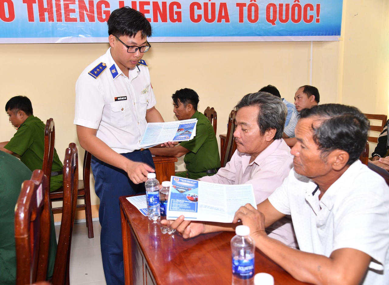 Cán bộ Bộ Tư lệnh Vùng Cảnh sát biển 4 phát tờ rơi tuyên truyền pháp luật cho ngư dân. (Ảnh: Quang Vinh)