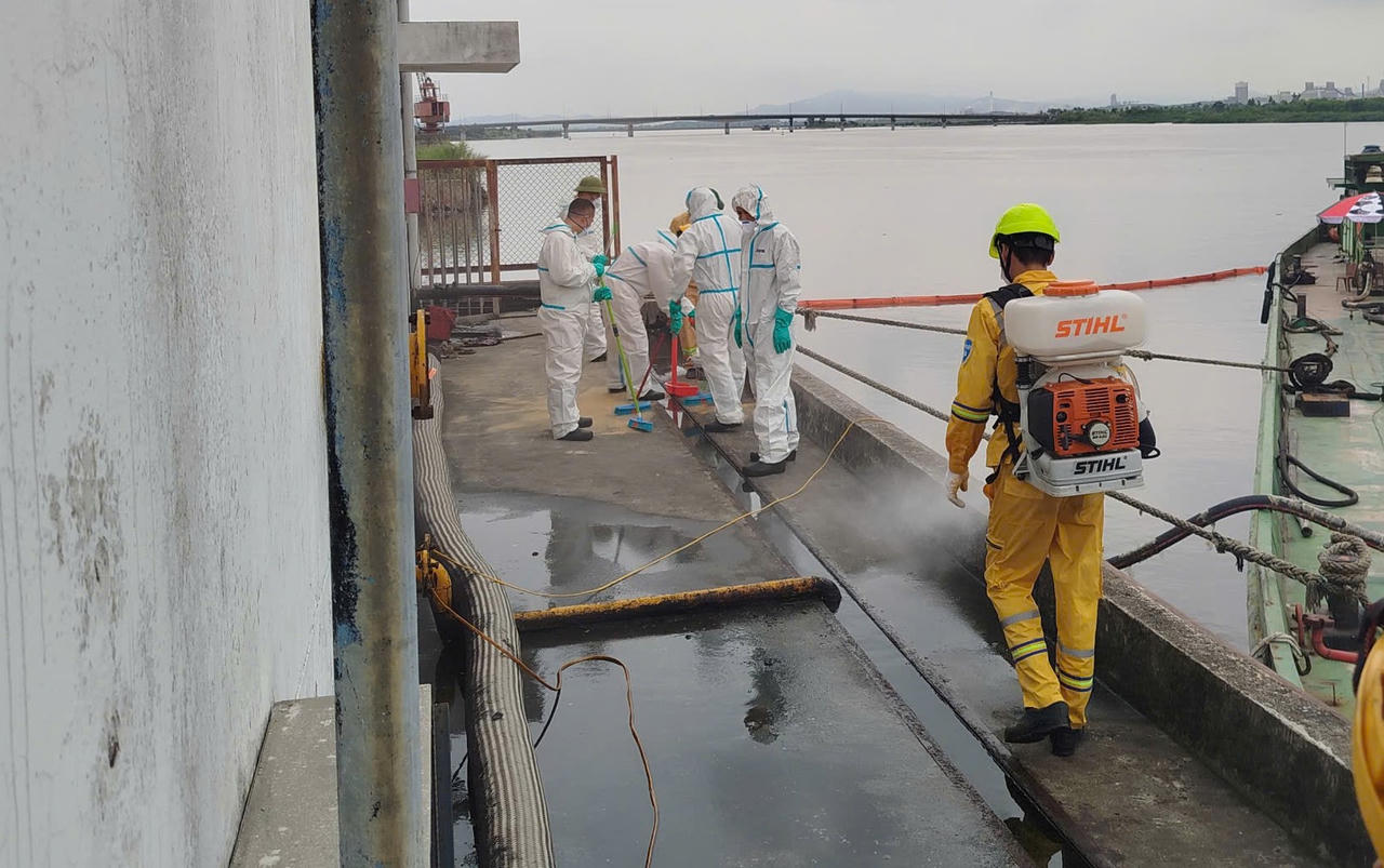 Lực lượng thu gom dầu bám trên mặt bằng cảng và tiến hành khử khuẩn.