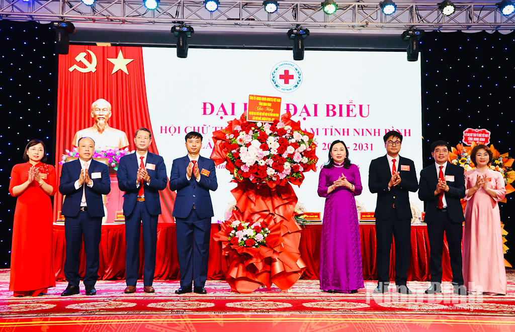 Bà Đinh Thị Lụa, Phó Bí thư Tỉnh ủy, Chủ tịch Ủy ban Mặt trận Tổ quốc Việt Nam tỉnh tặng hoa chúc mừng Đại hội. (Ảnh: Diệu Linh - Đức Lam)