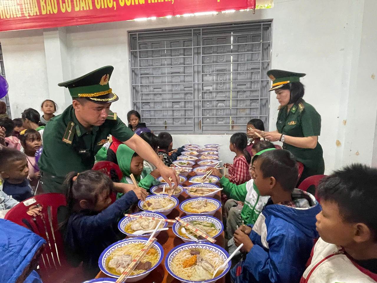Cán bộ Đồn Biên phòng Hướng Phùng cùng các thành viên đoàn thiện nguyện chuẩn bị, phục vụ bữa ăn miễn phí cho các em nhỏ.
