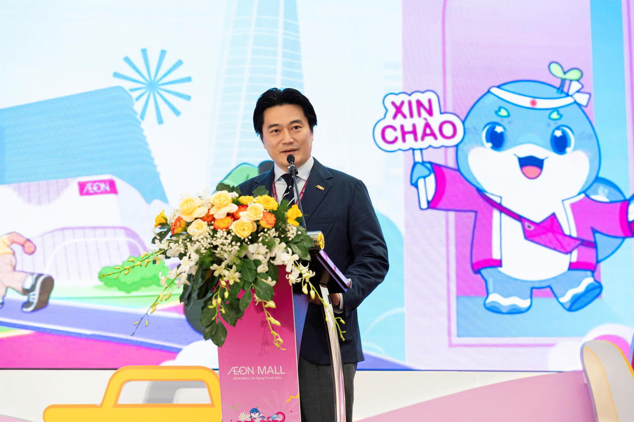 A person standing at a podium with a microphone and flowers

Description automatically generated