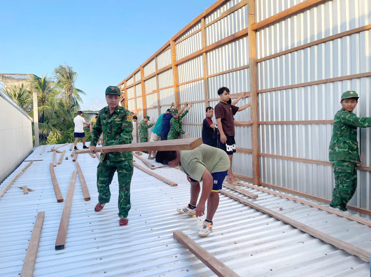 Cán bộ, chiến sĩ Đồn Biên phòng Đất Mũi vận chuyển vật liệu để dựng lại nhà cho bà Quỳnh.