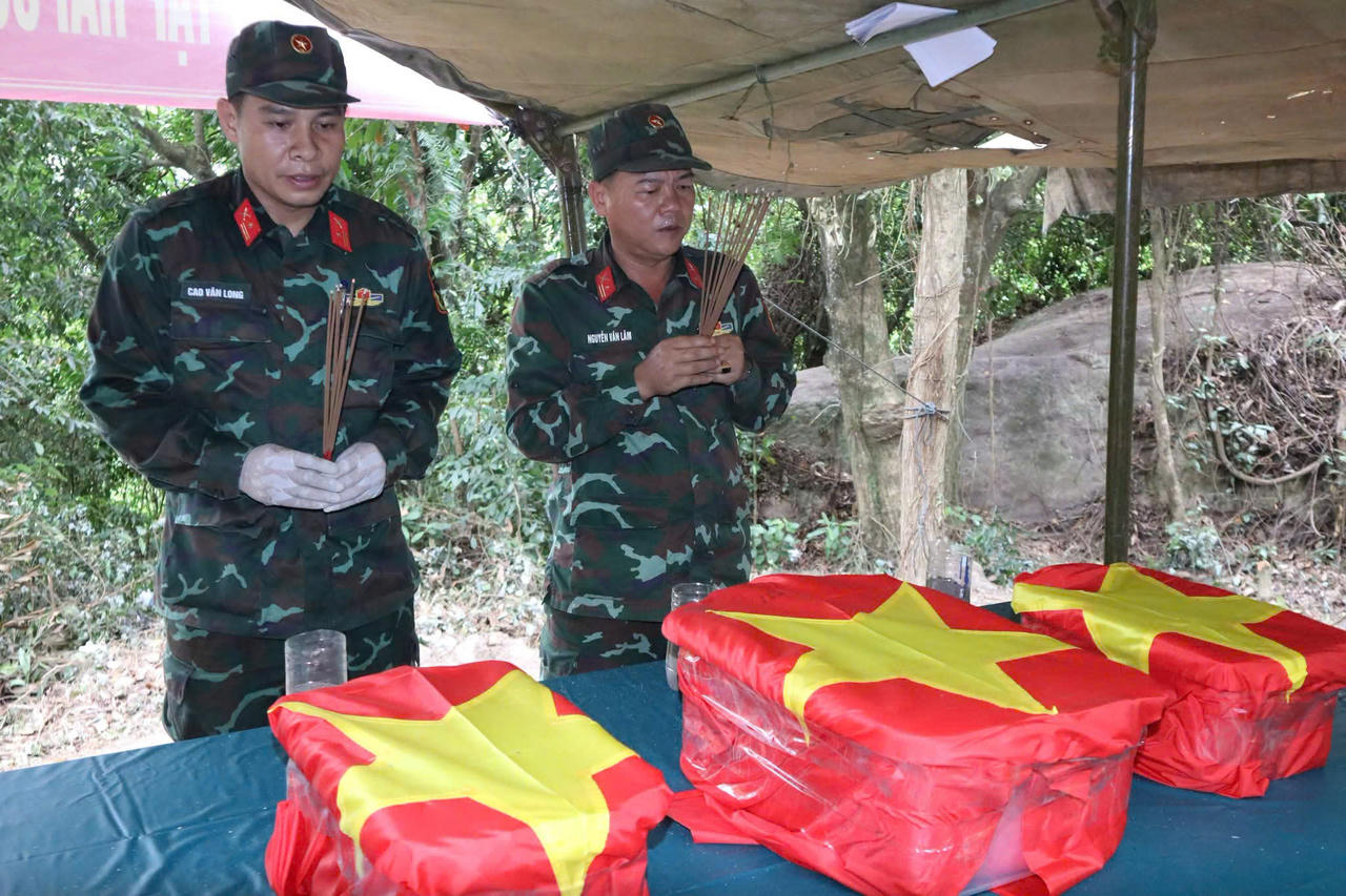 Ba bộ hài cốt đầu tiên được đưa lên từ hang Đá Sập ngày 13/7, phủ cờ Tổ quốc và đưa ra bên ngoài để đánh số thứ tự. Lực lượng tìm kiếm đồng thời mở rộng tìm kiếm. (Ảnh: Vân Anh)