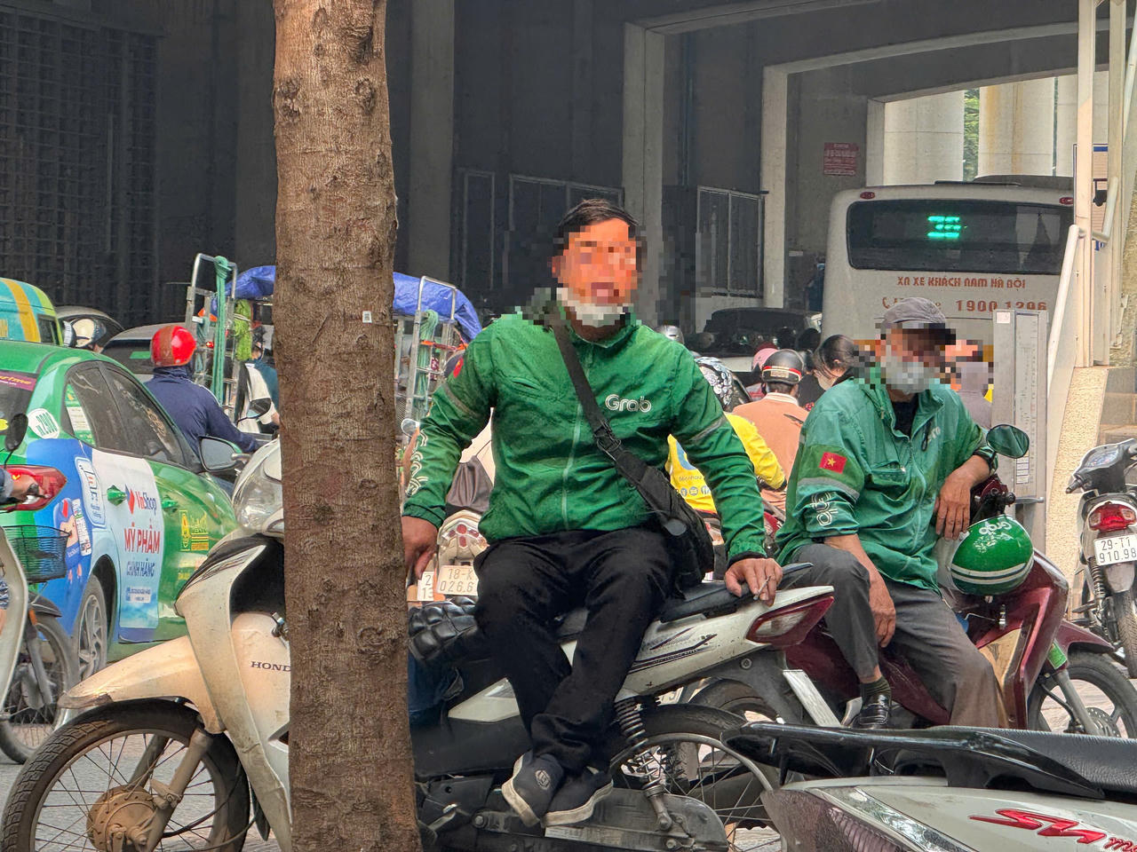Tài xế xe ôm công nghệ hút thuốc trong lúc chờ nhận cuốc xe tại khu vực trung tâm Hà Nội. (Ảnh: Thanh Hà)