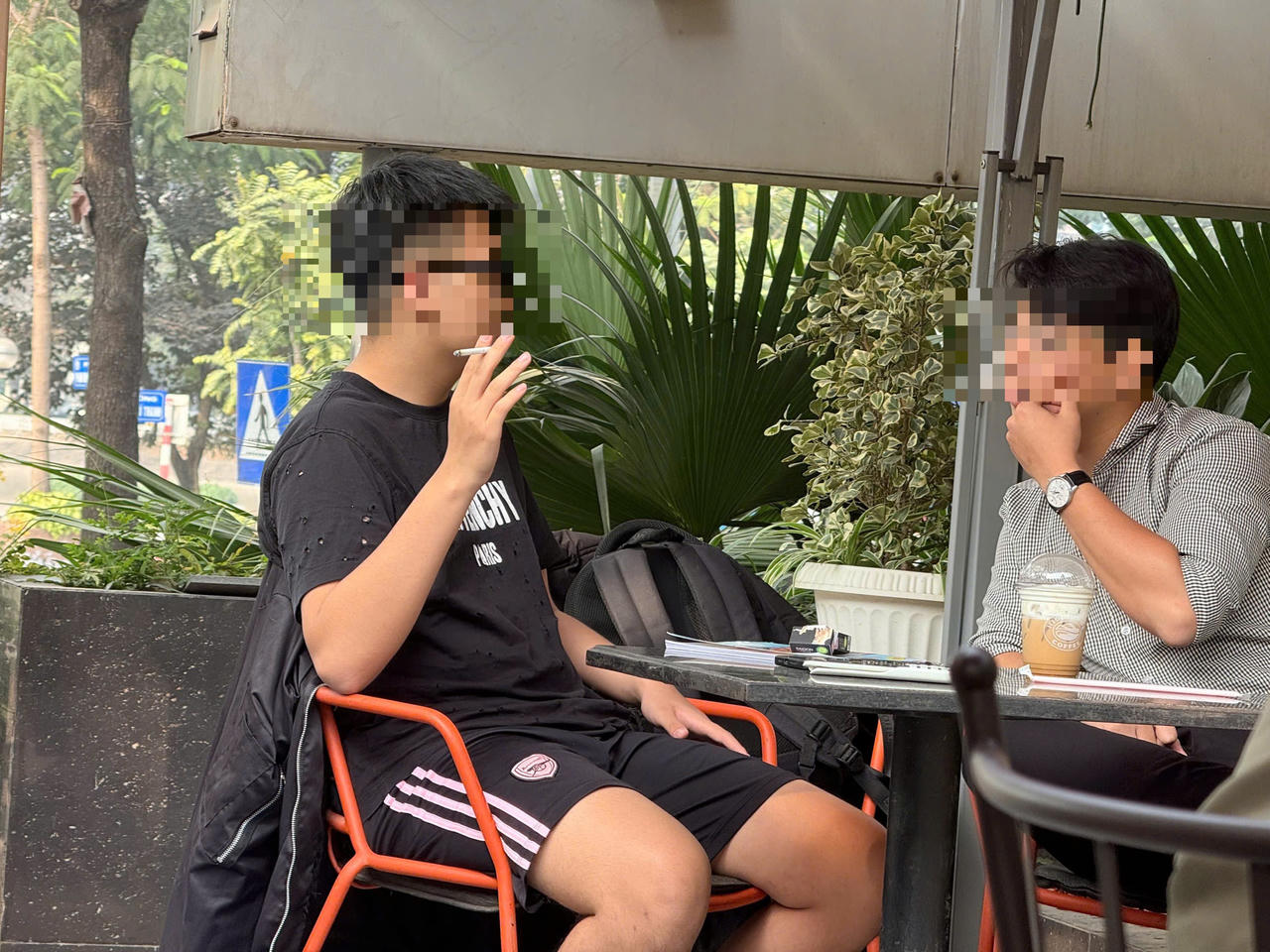 Nhiều người vẫn thản nhiên hút thuốc trong các quán cafe dù có biển cấm. (Ảnh: Thanh Hà).