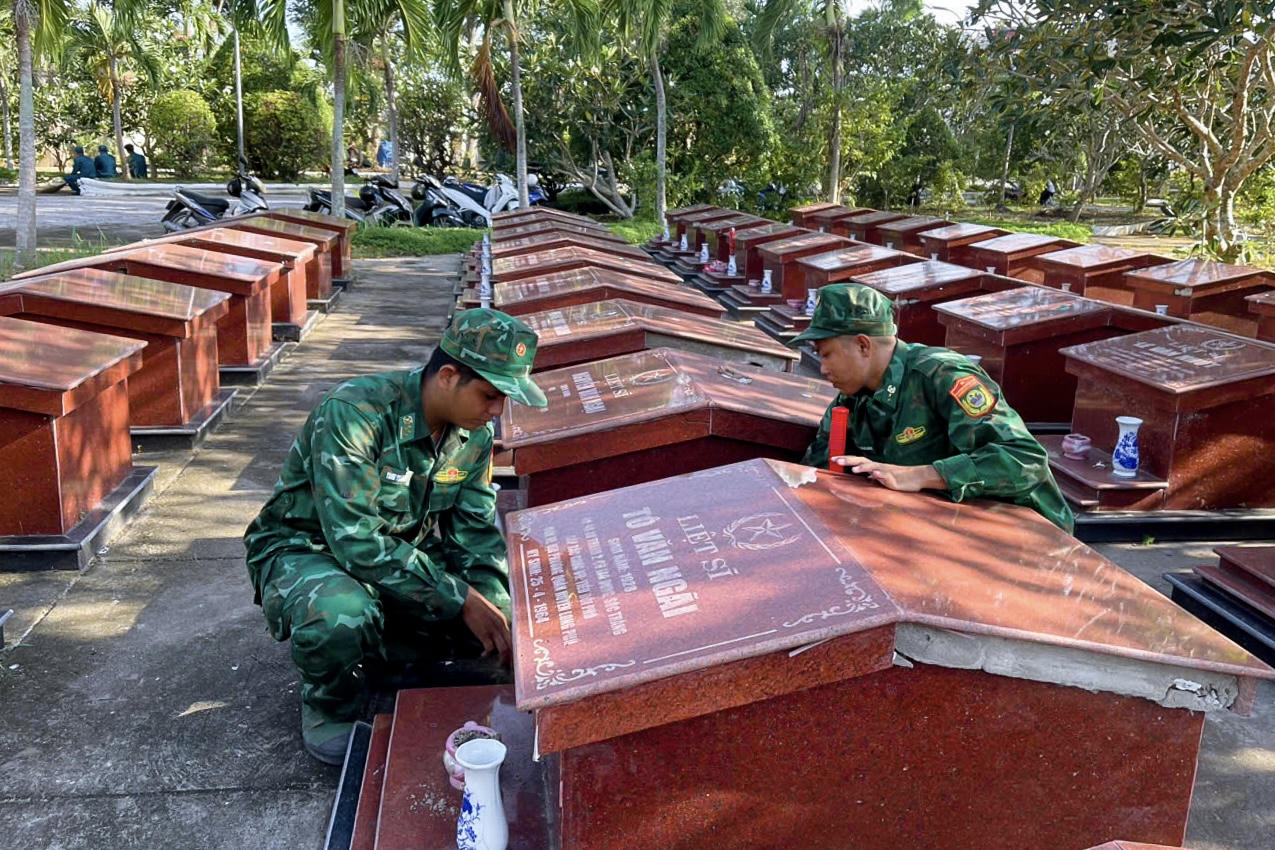 Cán bộ đồn Biên phòng An Thạnh Ba tham gia dọn vệ sinh, chỉnh trang Nghĩa trang Liệt sĩ. Ảnh: Văn Long
