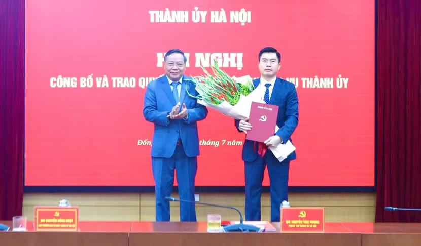 Phó bí thư Thành ủy Hà Nội Nguyễn Văn Phong trao quyết định, tặng hoa tân Bí thư phường Đống Đa Lê Tuấn Định (Ảnh: CTV).