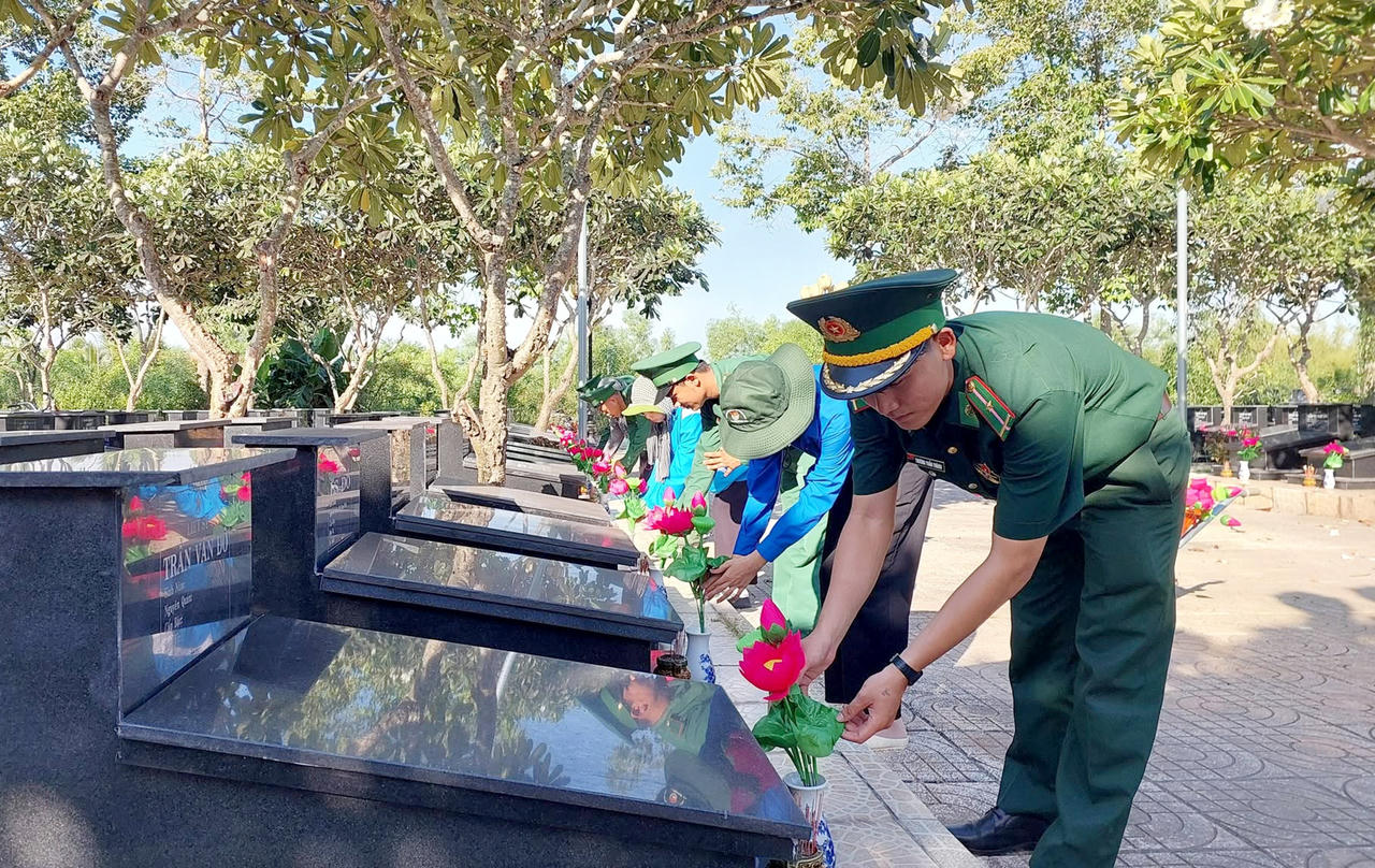 Chi đoàn Đồn Biên phòng Mỹ Thạnh Tây cùng cán bộ, đoàn viên thanh niên các đơn vị ra quân thực hiện mô hình “Ngàn hoa dâng mộ liệt sĩ”. Ảnh: Đinh Quân