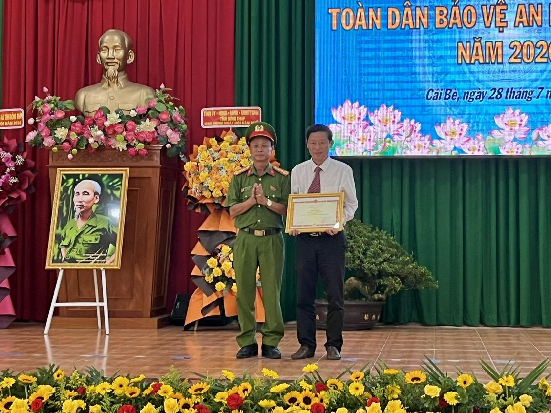Đại tá Trà Quang Thanh - Phó Giám đốc Công an tỉnh Đồng Tháp trao bằng khen của Bộ Công an cho Nhân dân và cán bộ xã Cái Bè, đại diện ông Nguyễn Thanh Việt Em - Phó Bí thư Đảng ủy, Chủ tịch UBND xã nhận. Ảnh: Thiện Lê