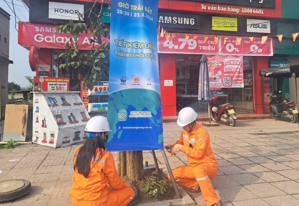 Cán bộ điện lực Hà Tĩnh treo băng rôn, poster tuyên truyền tiết kiệm điện tại các tuyến phố, khu vực đông dân cư. Ảnh: PV