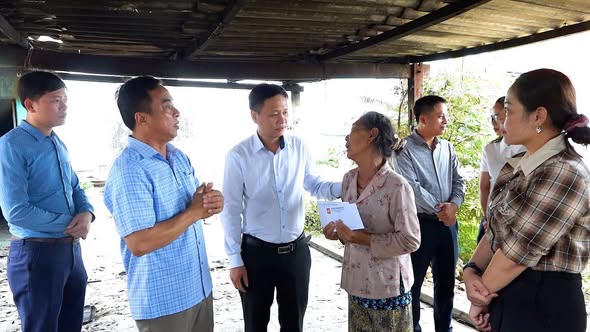 Ông Lê Minh Hiển, Phó Chủ tịch UBND phường Bắc Gianh (áo xanh nhạt) cùng các đoàn thể thăm hỏi, trao hỗ trợ bước đầu và động viên gia đình bà Trần Thị Câu sau vụ hỏa hoạn. (Ảnh T.A)