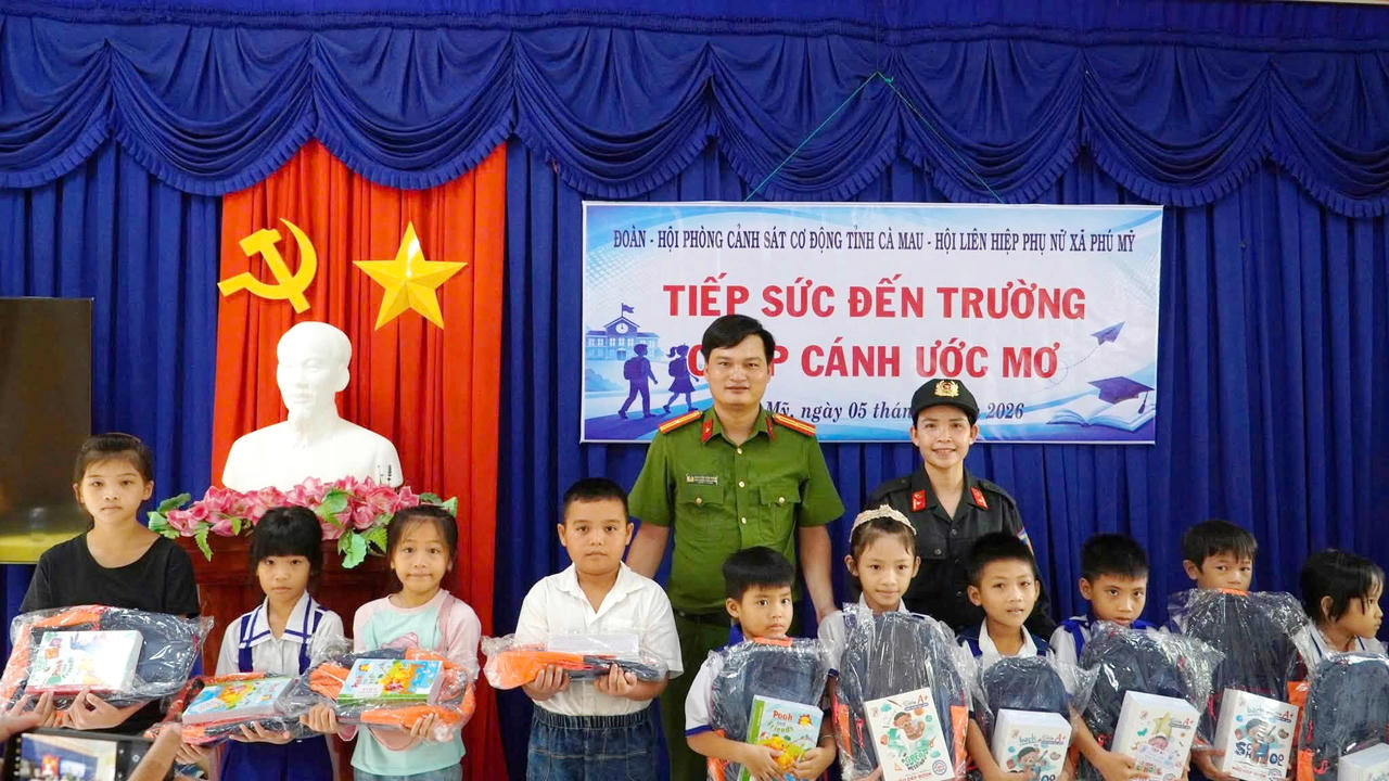 Cán bộ Phòng Cảnh sát cơ động Công an Cà Mau, phối hợp trao tặng ba lô, tập cho học sinh có hoàn cảnh khó khăn tại xã Phú Mỹ trước thềm năm học mới (Ảnh: Hữu Đệ).