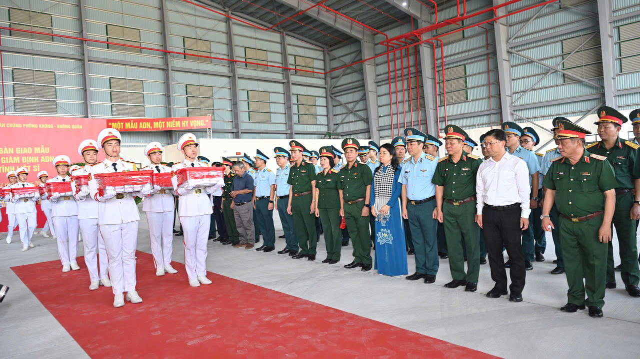 Các đại biểu thực hiện Nghi thức đưa mẫu sinh phẩm hài cốt các liệt sĩ lên máy bay quân sự. (Ảnh: Xuân Sang)