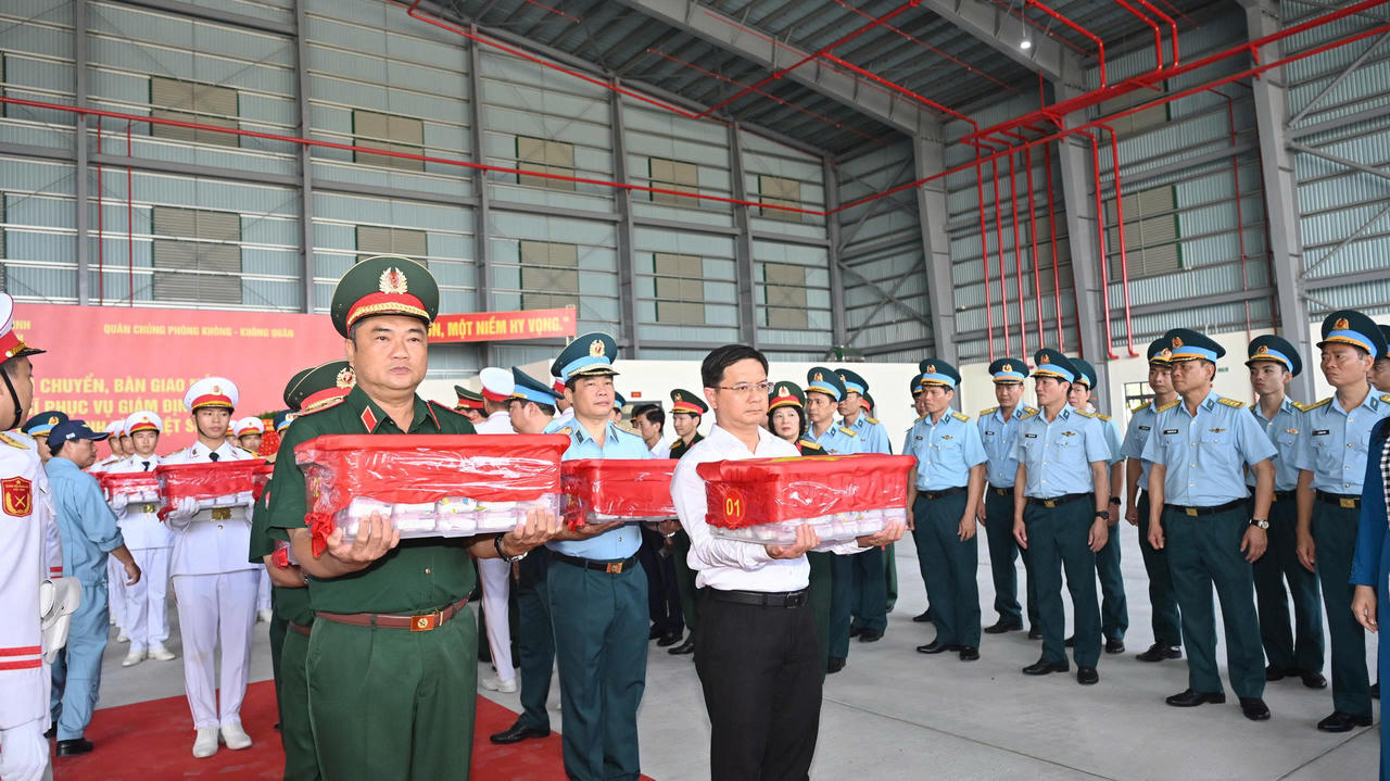 Trung tướng Lê Xuân Thế, Tư lệnh Quân khu 7 (bìa trái) và Ủy viên dự khuyết Trung ương Đảng, Phó chủ tịch UBND TP.HCM, Trưởng Ban Chỉ đạo 515 thành phố Nguyễn Mạnh Cường (sơ mi trắng) đưa thùng chứa mẫu sinh phẩm hài cốt liệt sĩ lên máy bay. (Ảnh: Xuân Sang)