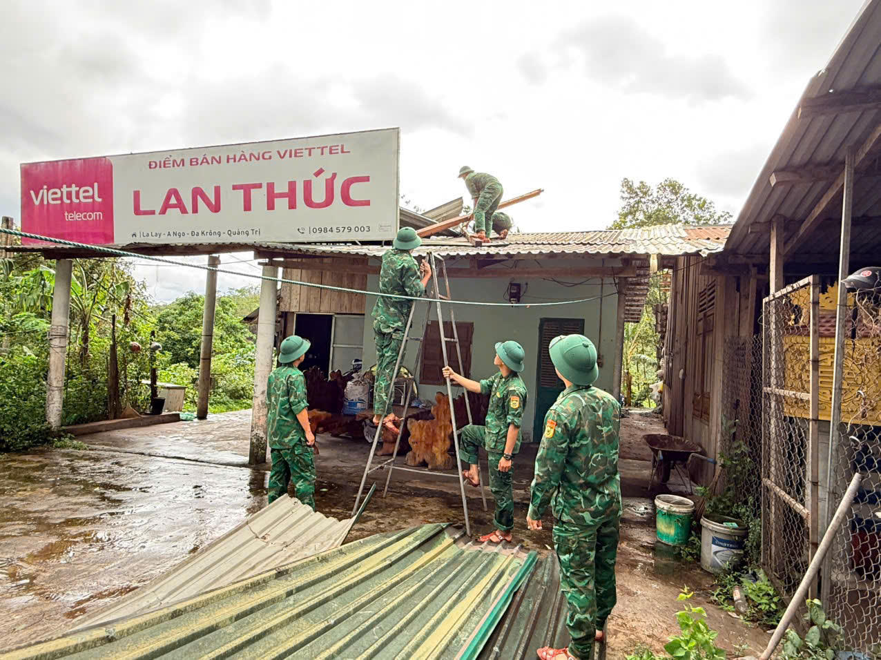 Lực lượng vũ trang phối hợp gia cố và lợp lại mái nhà cho 4 hộ dân bị thiệt hại. (Ảnh: Hoài Nam)