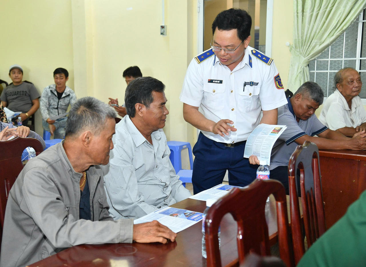 Cán bộ Bộ Tư lệnh Vùng Cảnh sát biển 4 phát tờ rơi tuyên truyền cho bà con ngư dân. Ảnh: Thanh Nghị