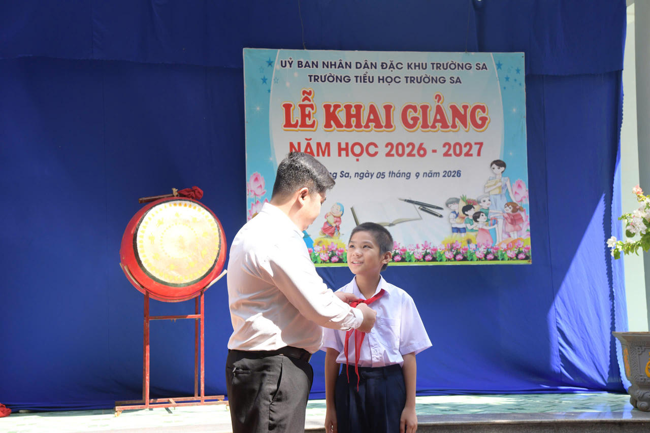 Thầy giáo Lê Xuân Hạnh trao khăn quảng đỏ cho học sinh Vi Quý Đăng.
