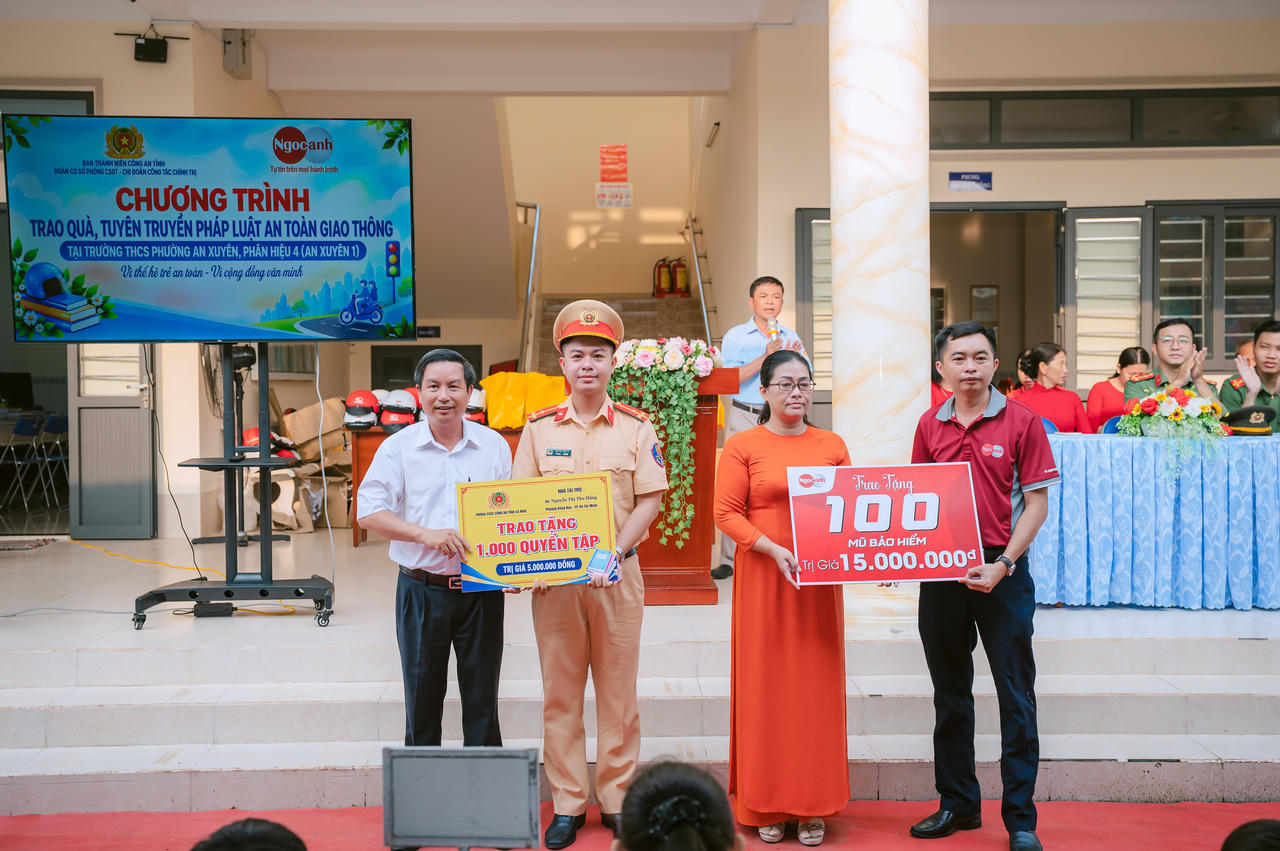 Đại diện đơn vị tài trợ trao biểu trưng 1.000 quyển tập và 150 mũ bảo hiểm cho Ban Giám hiệu Trường THCS phường An Xuyên, Phân hiệu 4. Ảnh: H.Đ.
