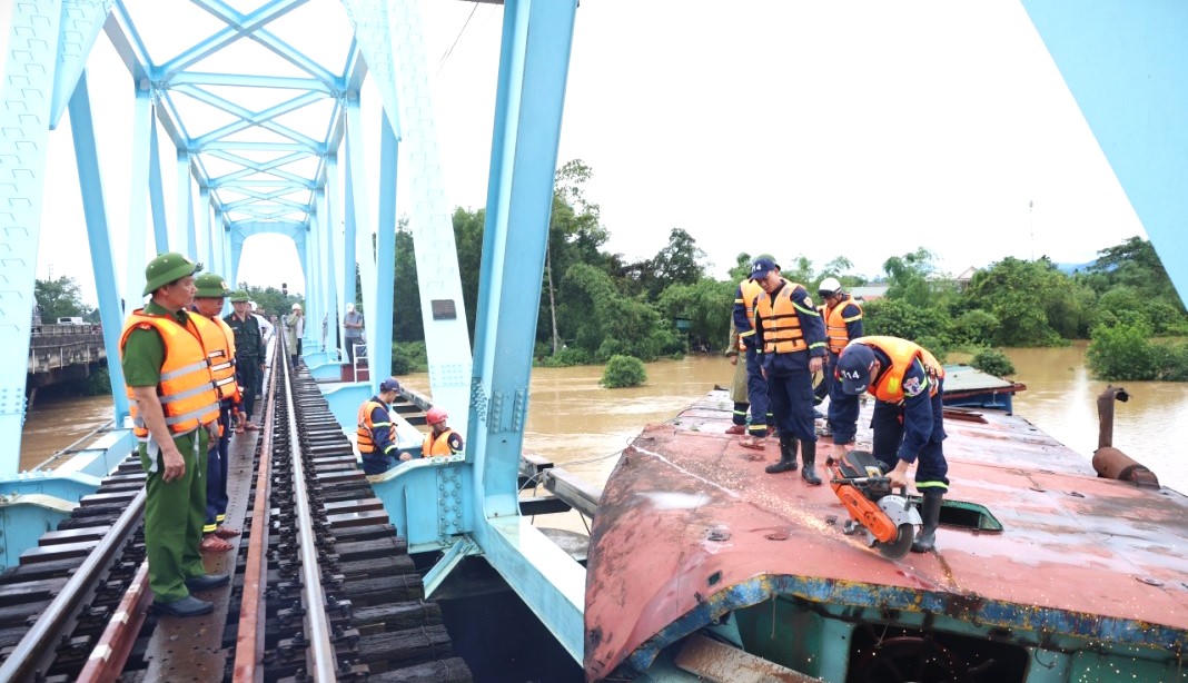 Lực lượng chức năng dùng thiết bị chuyên dụng cắt, tháo dỡ sà lan mắc kẹt tại cầu đường sắt Mỹ Chánh để giải phóng hiện trường, bảo đảm an toàn công trình. (Ảnh: CA Quảng Trị)