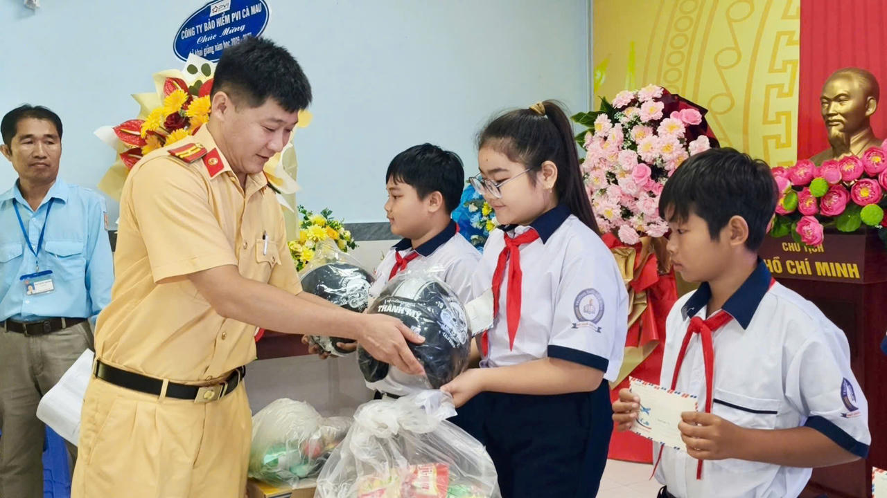 Cán bộ Phòng Cảnh sát giao thông trao quà, tặng mũ bảo hiểm cho học sinh Trường THCS Hòa Bình (Ảnh: H.Đ).