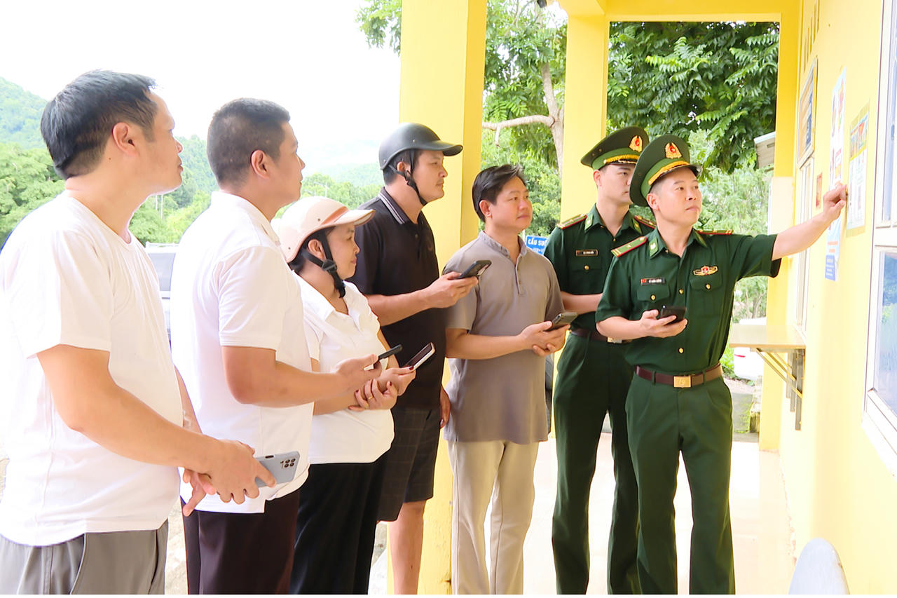 Cán bộ Đồn Biên phòng cửa khẩu Tén Tằn hướng dẫn người dân sử dụng tiện ích số, làm thủ tục qua lại biên giới và quét mã QR tố giác tội phạm (Ảnh: HC).
