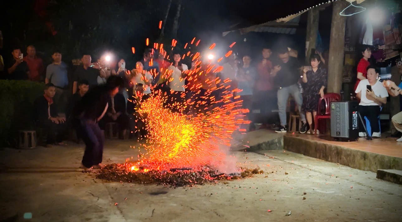 Sau phần nghi lễ, những chàng trai Dao đỏ lần lượt tiến về phía đống than hồng. Những bước chân mạnh mẽ trên nền than đỏ tạo nên màn trình diễn ấn tượng, thu hút sự chú ý của đông đảo người dân và du khách (Ảnh: Nguyễn Hải).