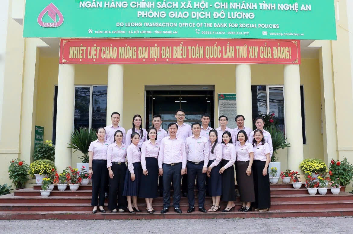 Giám đốc NHCSXH tỉnh Nghệ An - ông Hoàng Xuân Thuỷ (người đứng hàng đầu thứ 5 từ trái sang) gặp gỡ và chúc mừng tập thể cán bộ nhân viên NHCSXH Đô Lương đạt thành tích tăng trưởng dư nợ lên 1.000 tỷ đồng