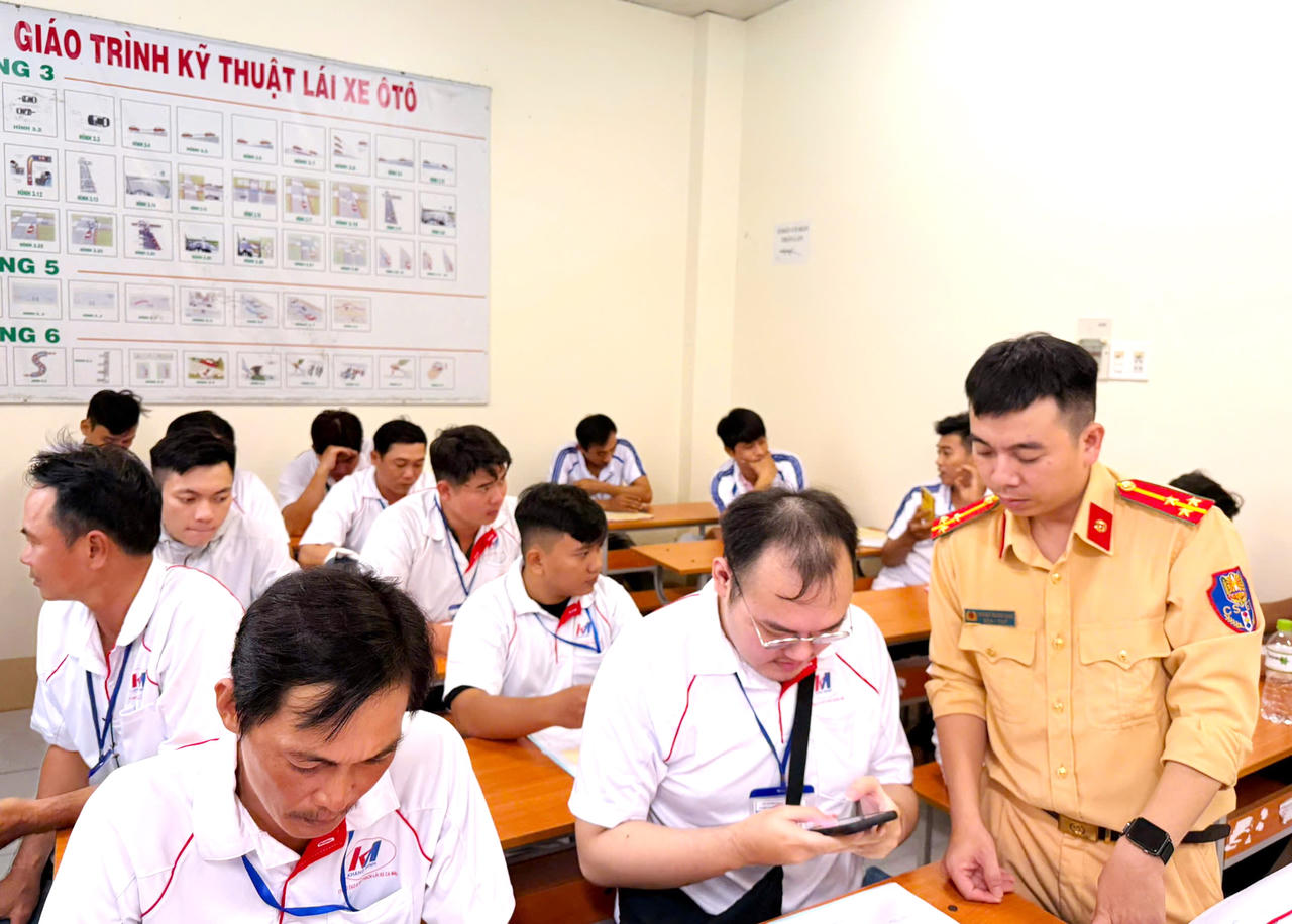 Cán bộ Cảnh sát giao thông hướng dẫn công dân cài đặt, sử dụng ứng dụng VNeTraffic trước khi tham gia kỳ sát hạch (Ảnh: H.Đ).