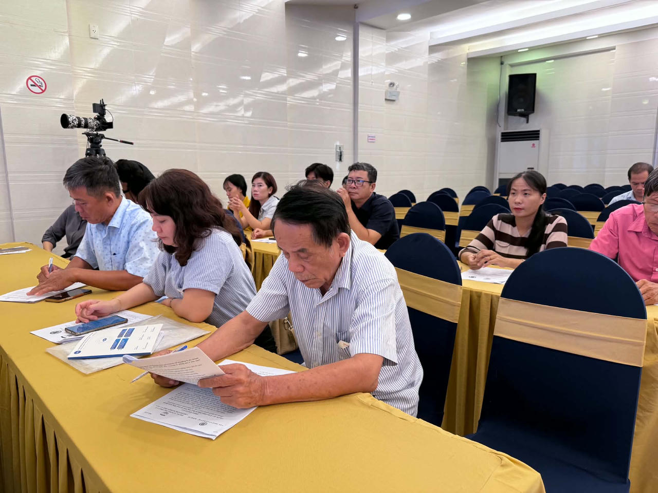 Đại diện các doanh nghiệp, hộ kinh doanh nghiên cứu tài liệu về các quy định pháp luật liên quan đến lao động, tiền lương và BHXH tại hội nghị. (Ảnh: T.Nhung)