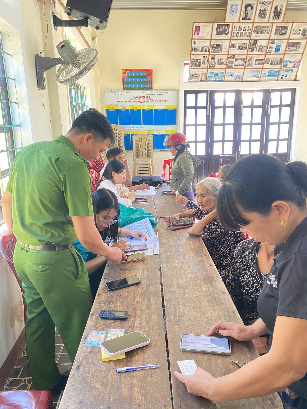 Công an xã Trung Thuần hướng dẫn người dân sử dụng định danh điện tử trên ứng dụng VNeID. (Ảnh: M.P)