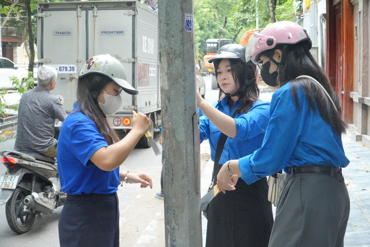 Đoàn viên, thanh niên tham gia bóc, xóa quảng cáo, rao vặt trái phép tại Hà Nội. (Ảnh: Huy Hoàng)