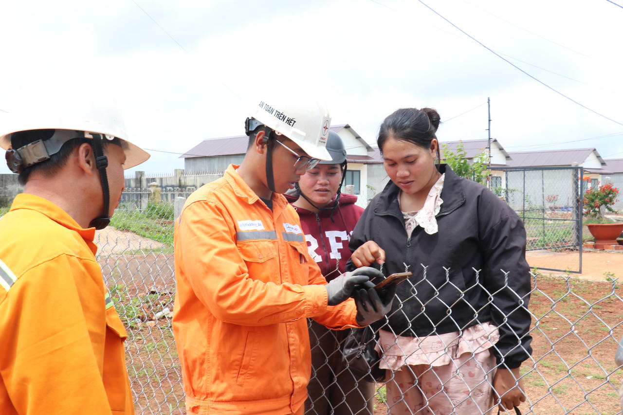 Nhân viên điện lực hướng dẫn người dân sử dụng ứng dụng EVN CSKH để thực hiện các dịch vụ điện trực tuyến. Ảnh: EVNSPC