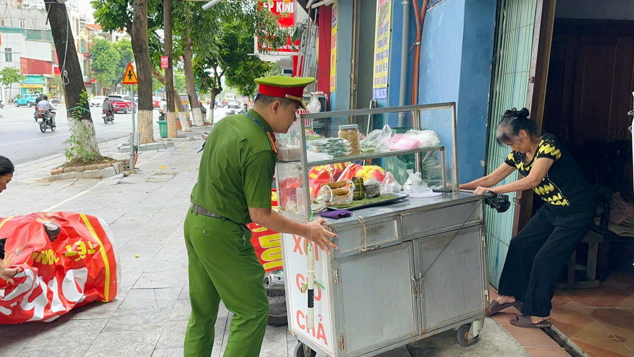 Lực lượng công an hỗ trợ người dân di chuyển vật cản lấn chiếm lòng, lề đường, vỉa hè (Ảnh: CACC).