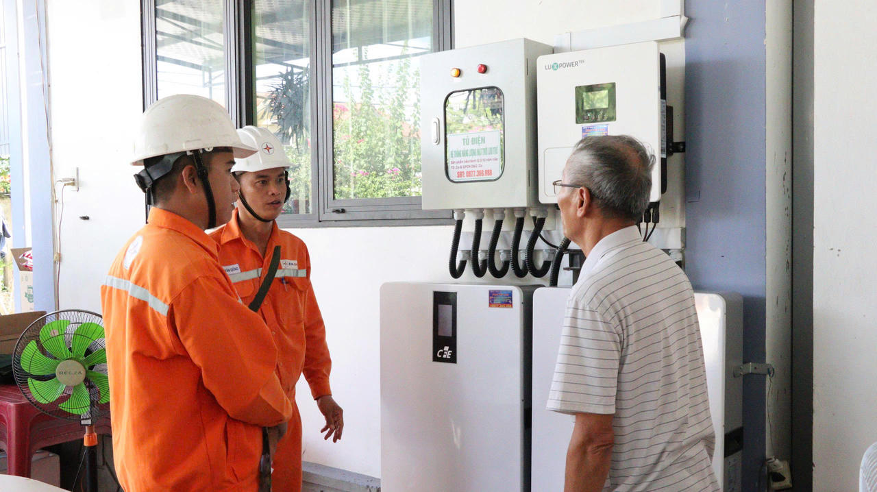 Nhân viên điện lực hướng dẫn người dân kiểm tra, vận hành hệ thống điện mặt trời mái nhà kết hợp lưu trữ điện. (Ảnh: H.N)