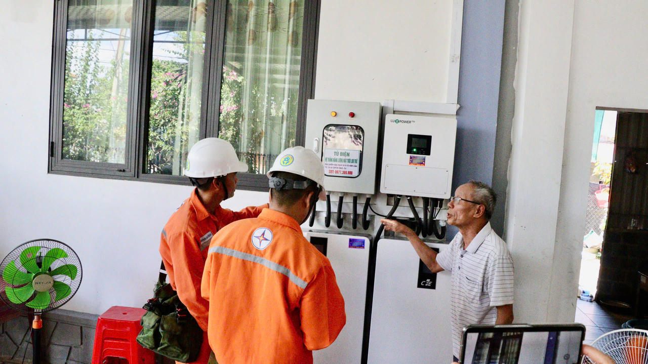 Nhân viên điện lực hướng dẫn người dân kiểm tra, vận hành hệ thống điện mặt trời mái nhà kết hợp lưu trữ điện. (Ảnh: H.N)